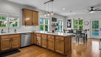 A modern kitchen with wooden cabinets, a built-in dishwasher, and a large island.