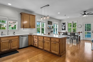 A modern kitchen with wooden cabinets, a built-in dishwasher, and a large island. - Gather at Smith Lake | Boat Ramp | Sleeps up to 10 | Crane Hill lakefront home (Crane Hill)