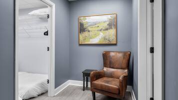 Une pièce avec un lit superposé, une chaise, une petite table et un tableau représentant un paysage accroché au mur.