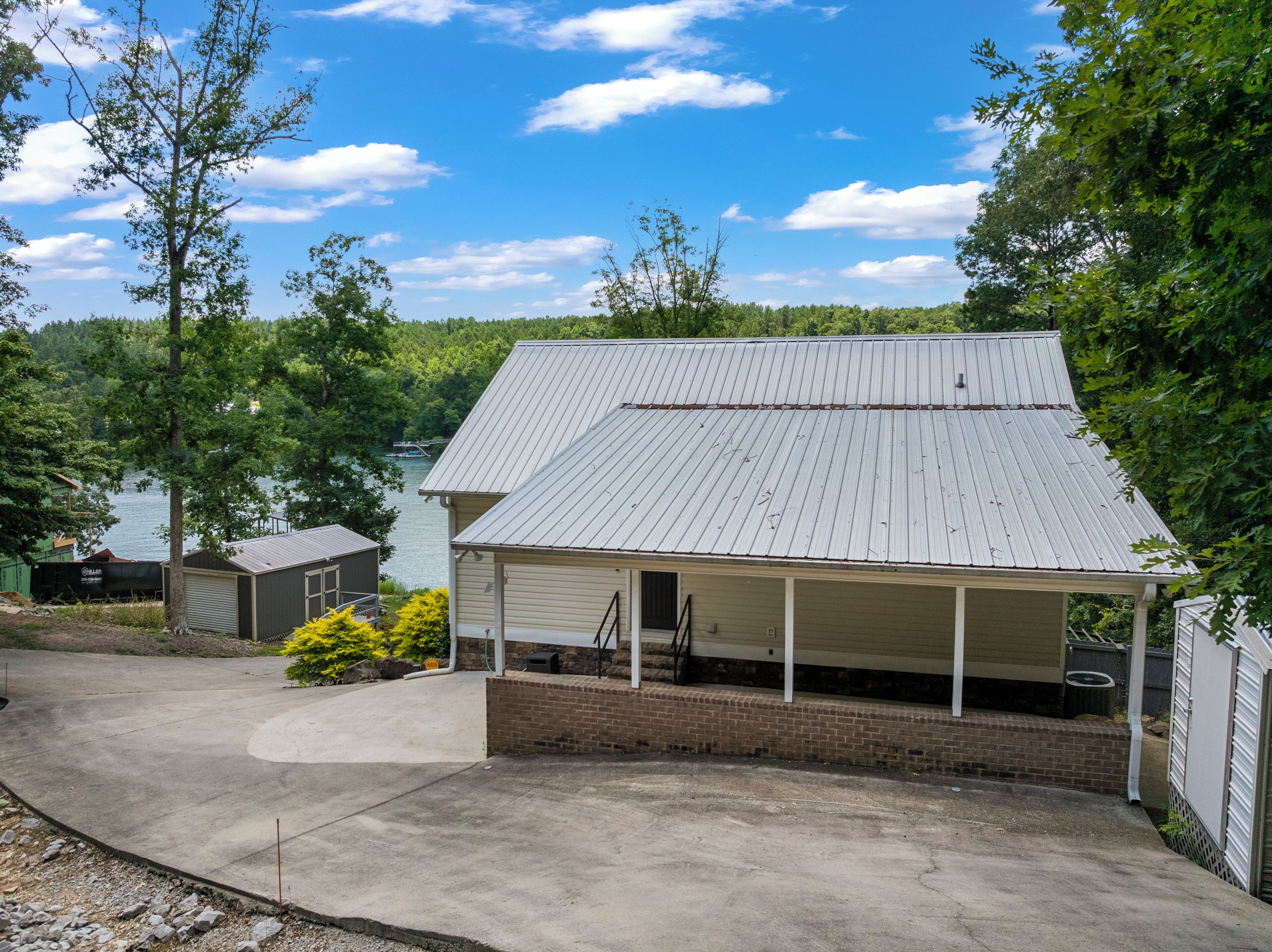 A single-story building with a covered porch, a brick foundation, and a metal roof.