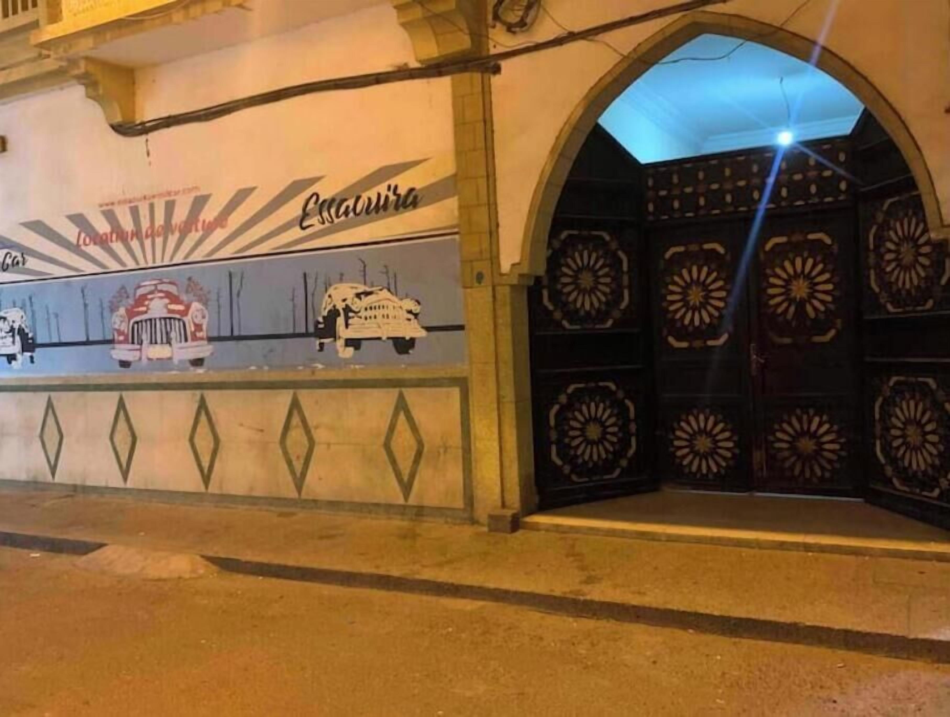 Une entrée d’immeuble dotée d’un grand portail en arc de cercle et de panneaux décoratifs.