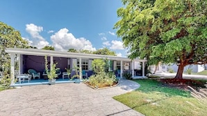 Ein Haus mit überdachter Veranda, Blumentöpfen und einem gepflegten Rasen.