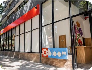 A building with large windows, a red awning, and a sign with a flower and the word 'bloom'. - Laureles Loft - View of the Stadium - 5-minute walk to the Metro (Medellín)