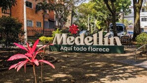 Medellín-kyltti, jossa lukee teksti ”Aquí todo florece” ja on punainen kukka -aiheinen kuvio.