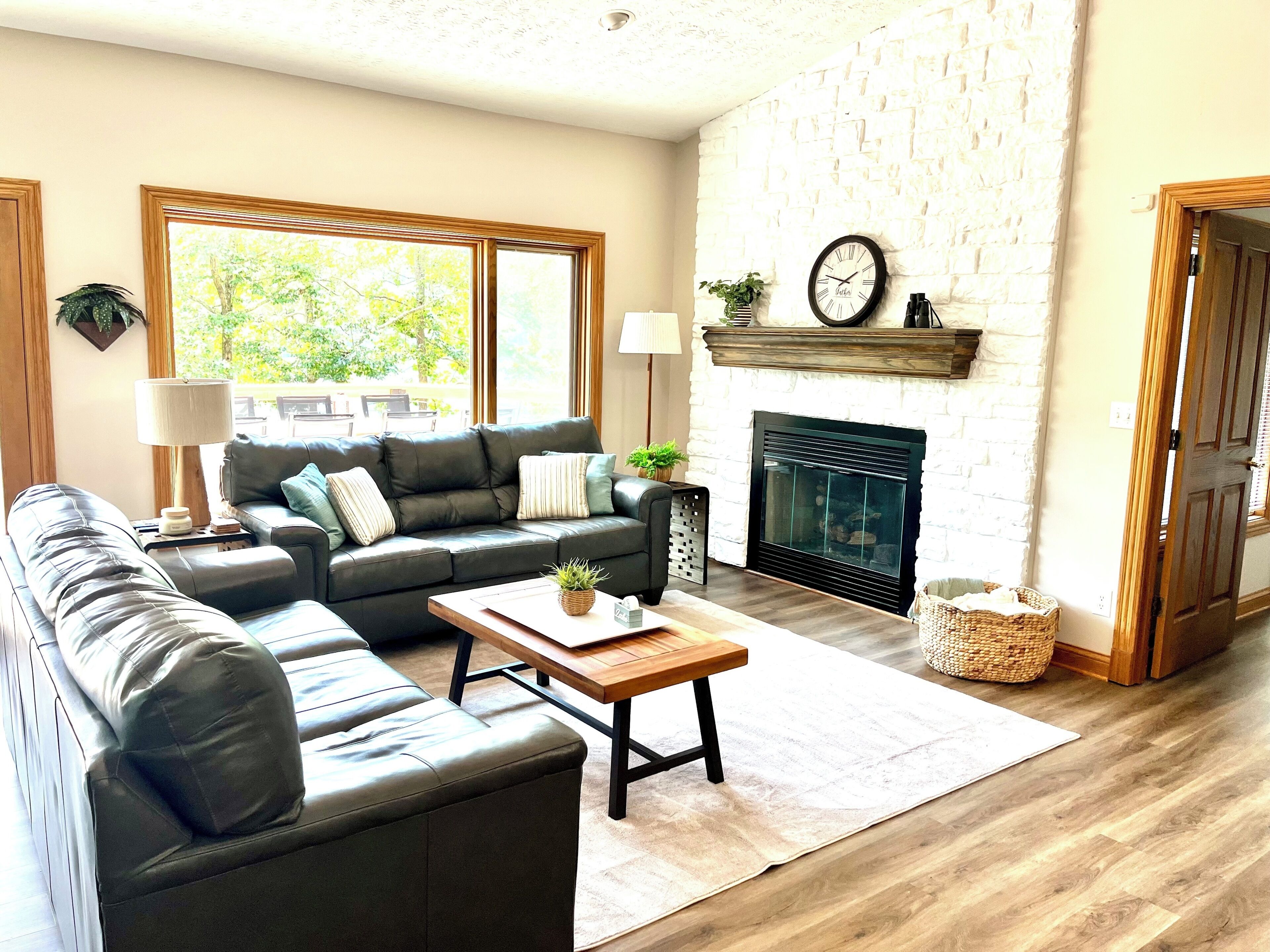 A living room with a fireplace, a sofa, a coffee table, and a large window.