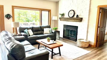 A living room with a fireplace, a sofa, a coffee table, and a large window.