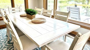 Een eettafel met stoelen, een hangplant en geweven placemats.