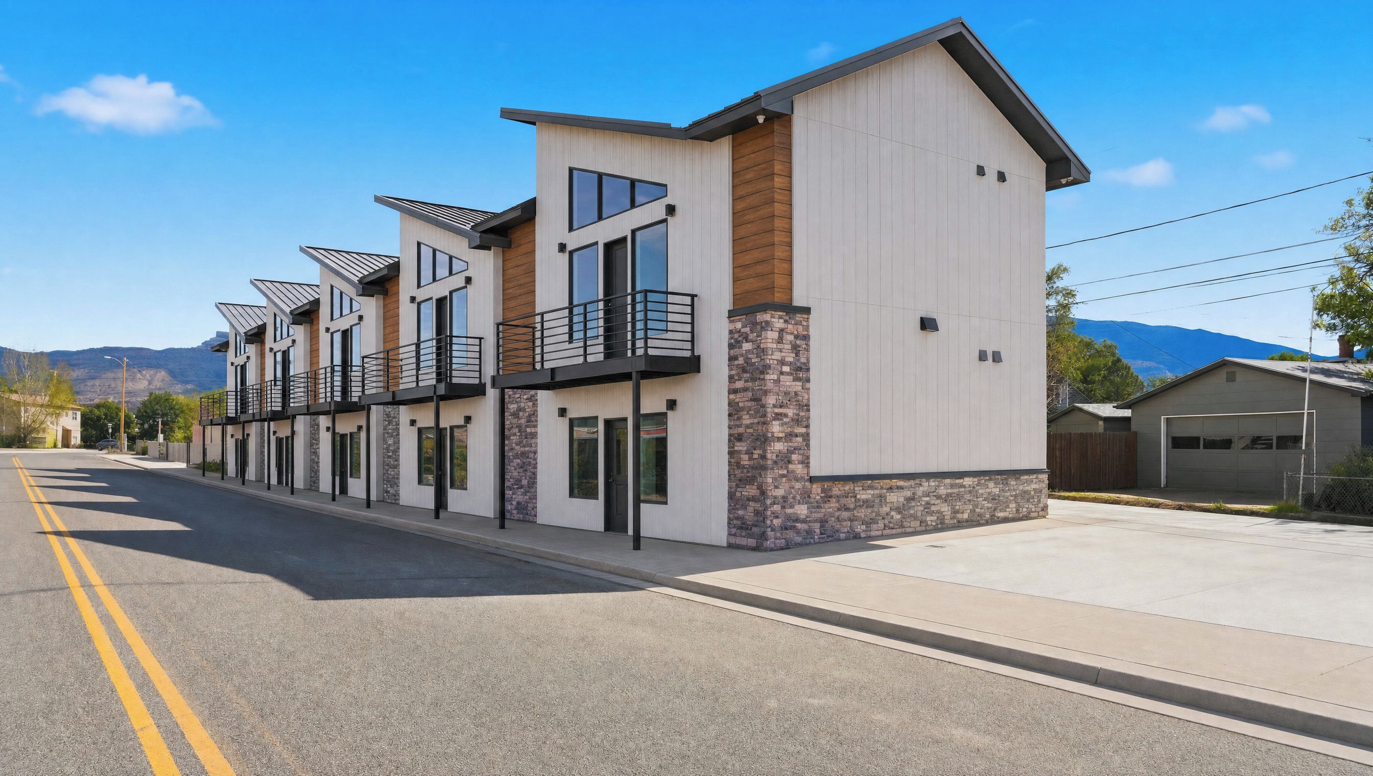 A modern multi-story residential building with a flat roof, large windows, and a stone accent wall.