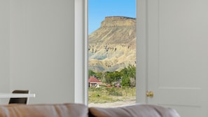 A bedroom with a bed and a door leading to a view of a mountainous landscape.