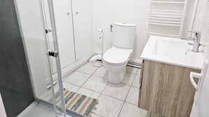 Un baño con inodoro, lavamanos y zona de ducha.