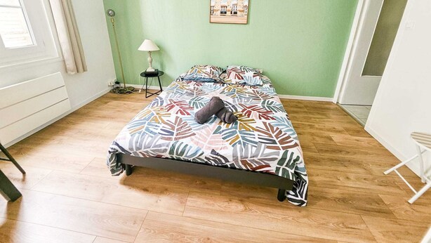 Un dormitorio con cama, lámpara, un cuadro enmarcado en la pared y una ventana.