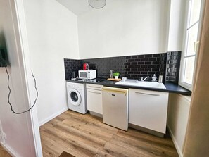 Eine kleine Küche mit Waschmaschine, Mikrowelle und Spüle.