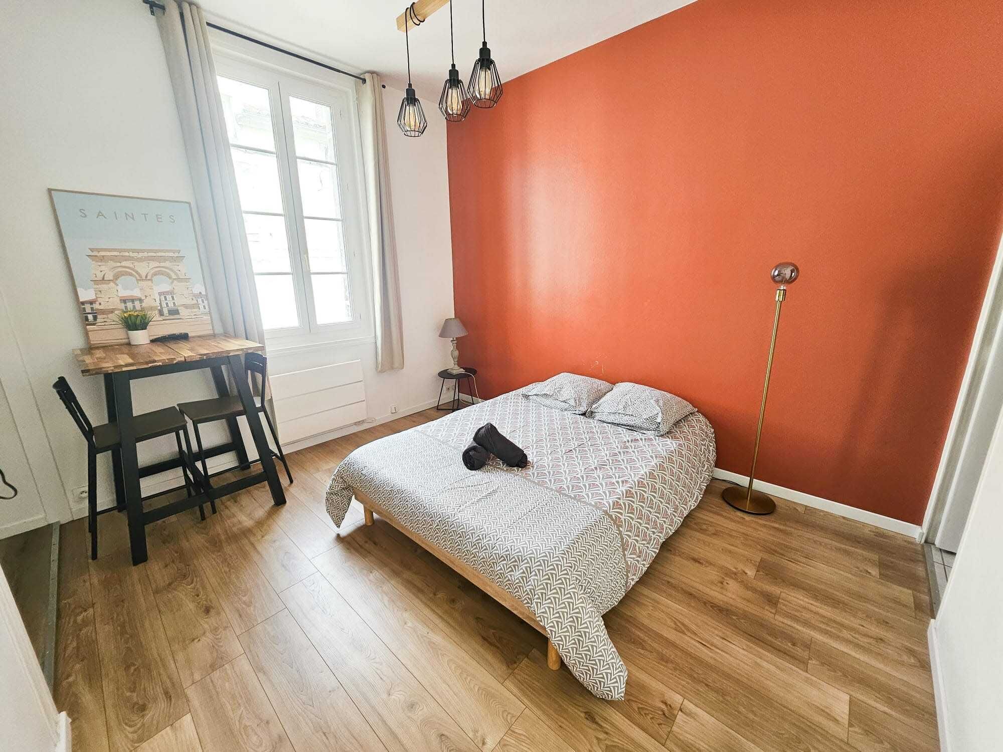 A bedroom with a bed, a desk, and a chair.