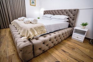 A bedroom with a tufted headboard, a bed with white linens, rolled towels, and a bedside plant. - AUREA ROME ANTIQUE ROOMS (Rome)