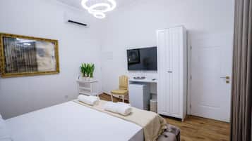 A hotel room with a bed, a desk, a television, a wardrobe, and a mirror.
