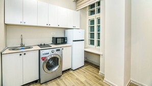 Uma cozinha compacta com máquina de lavar, micro-ondas e frigorífico.