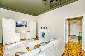 Ein Wohnzimmer mit einer Couch, einem Couchtisch, einem Kamin und einem Fernseher an der Wand.