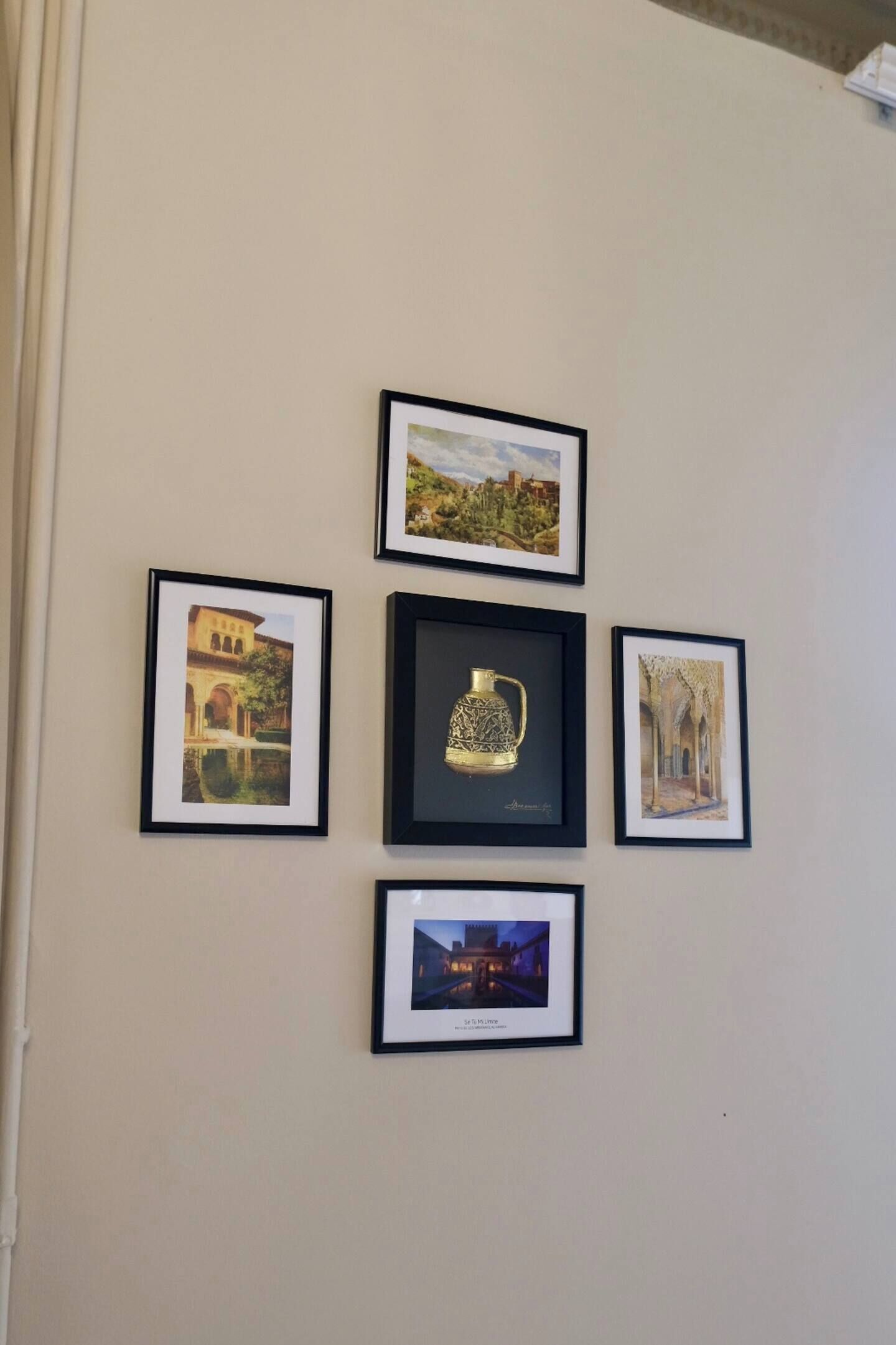 A wall with five framed pictures, including a central framed object.