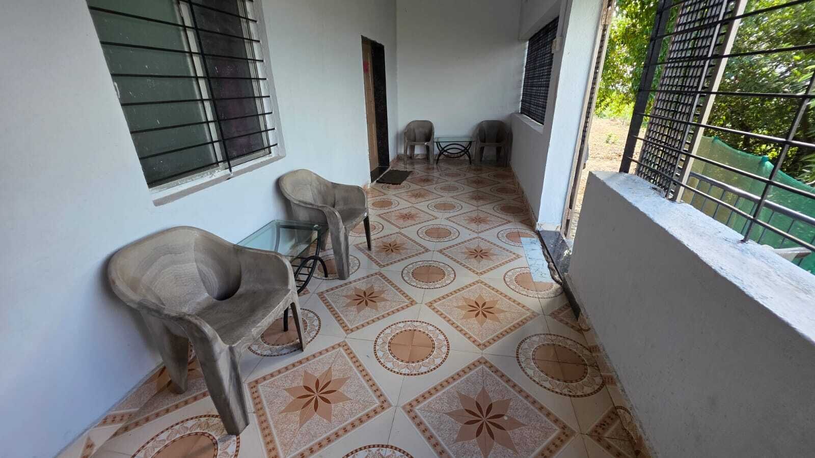 A corridor with patterned flooring, two chairs, a small table, and a window with bars.