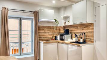 A compact kitchen with a window, a sink, a coffee maker, and a microwave.