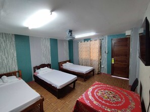 A hotel room with three wooden beds, a red patterned bedspread, a ceiling fan, and a TV mounted on the wall. - Donya Thelma Ferrer Spring Resort (Dumalag)