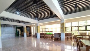 A spacious indoor area with a polished floor, wooden furniture, and large windows allowing natural light.