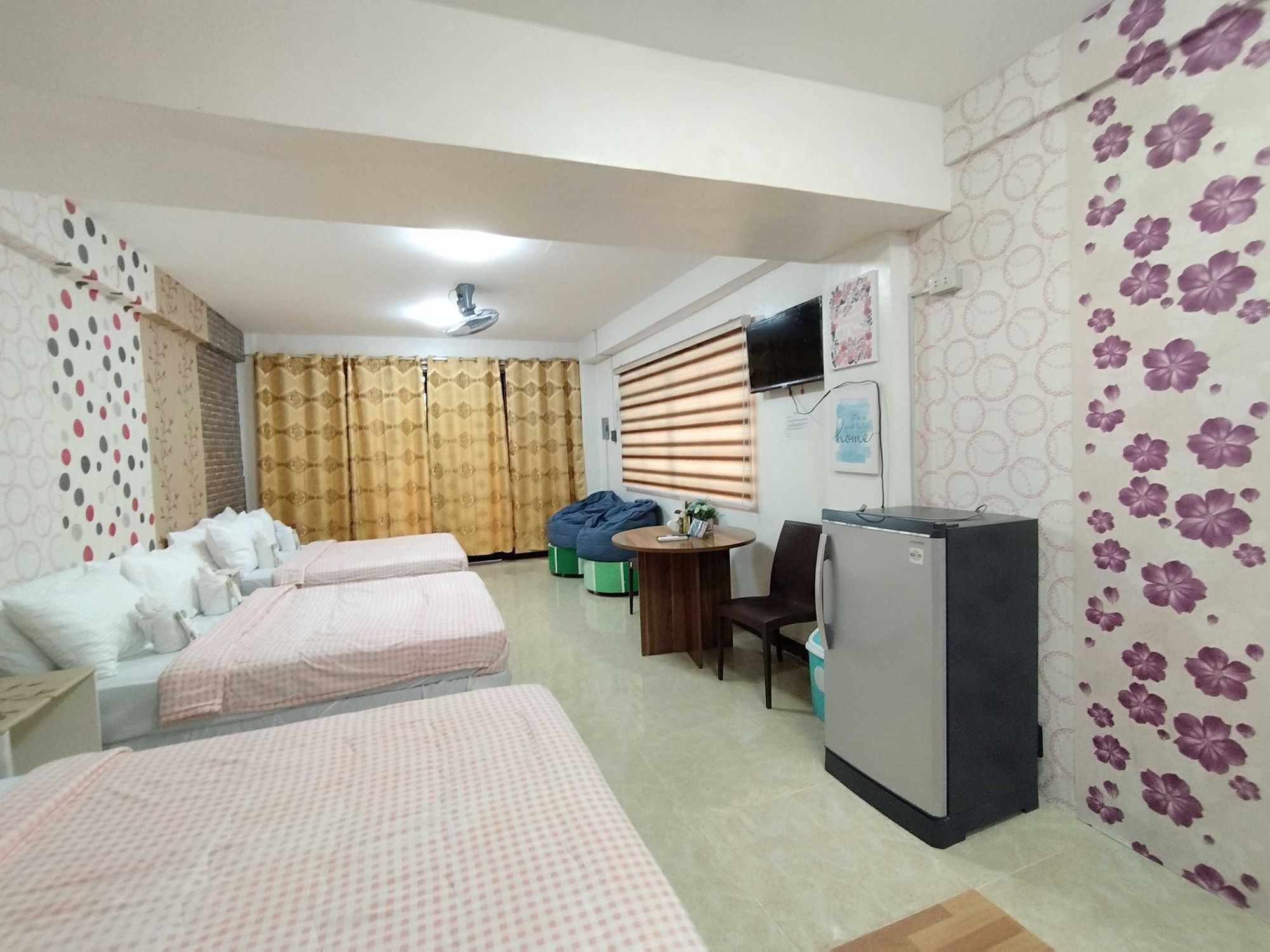 A hotel room with two beds, a small table, a chair, a television, and a refrigerator.