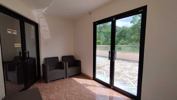 A room with two chairs, a small table, and a sliding glass door leading to an outdoor area with a patterned floor.
