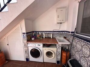 Een praktische wasruimte met een wasmachine, droger en een klein wasbakje.