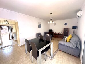 A living room with a dining table, chairs, a sofa, a TV, and a lamp. - R1399, Casa Nina Pariles, Maro (Maro)