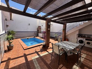 A patio with a swimming pool, a table with chairs, a brick oven, and a laundry area. - R1399, Casa Nina Pariles, Maro (Maro)