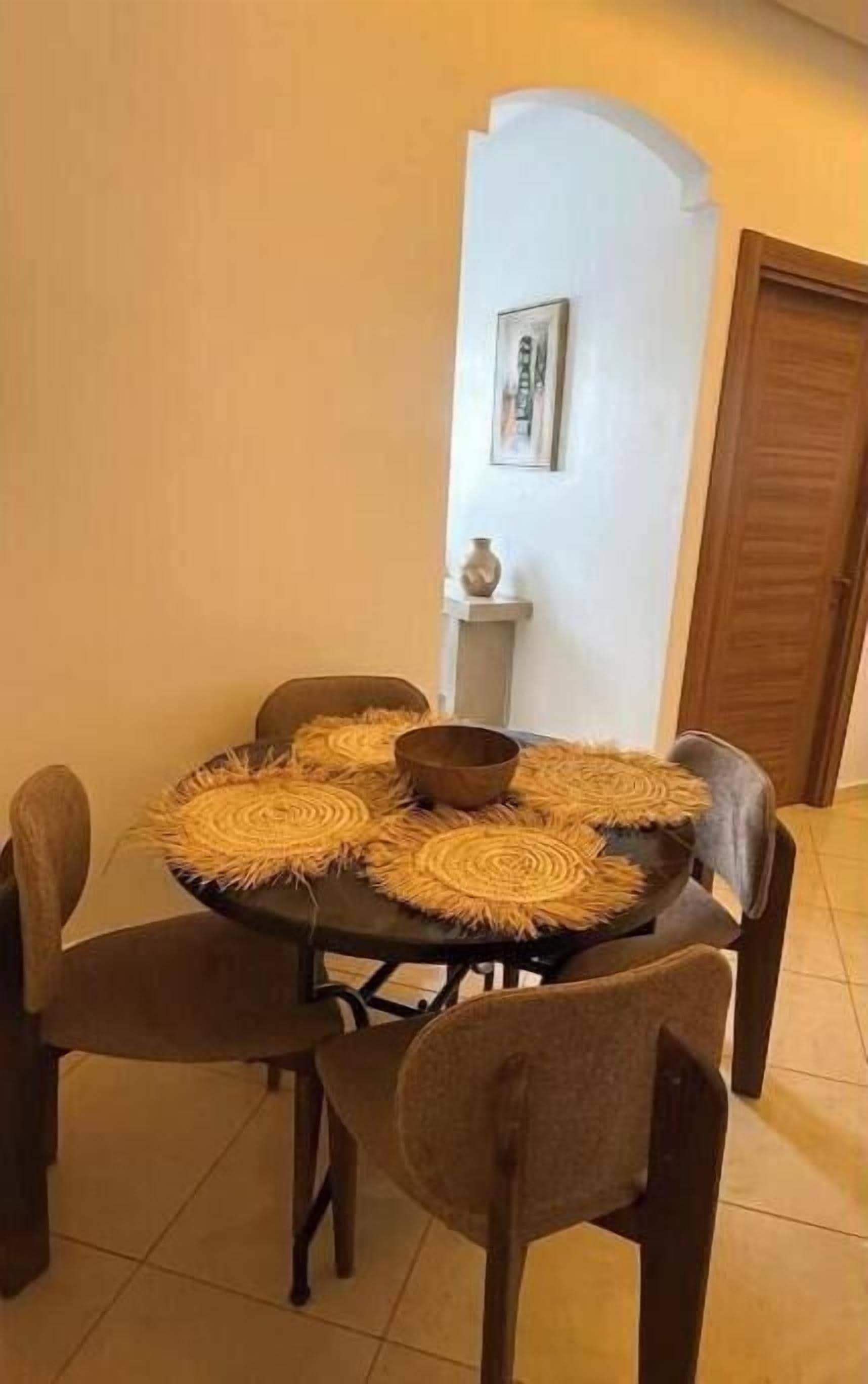 Una mesa de comedor con un camino de mesa tejido, rodeada de cuatro sillas.