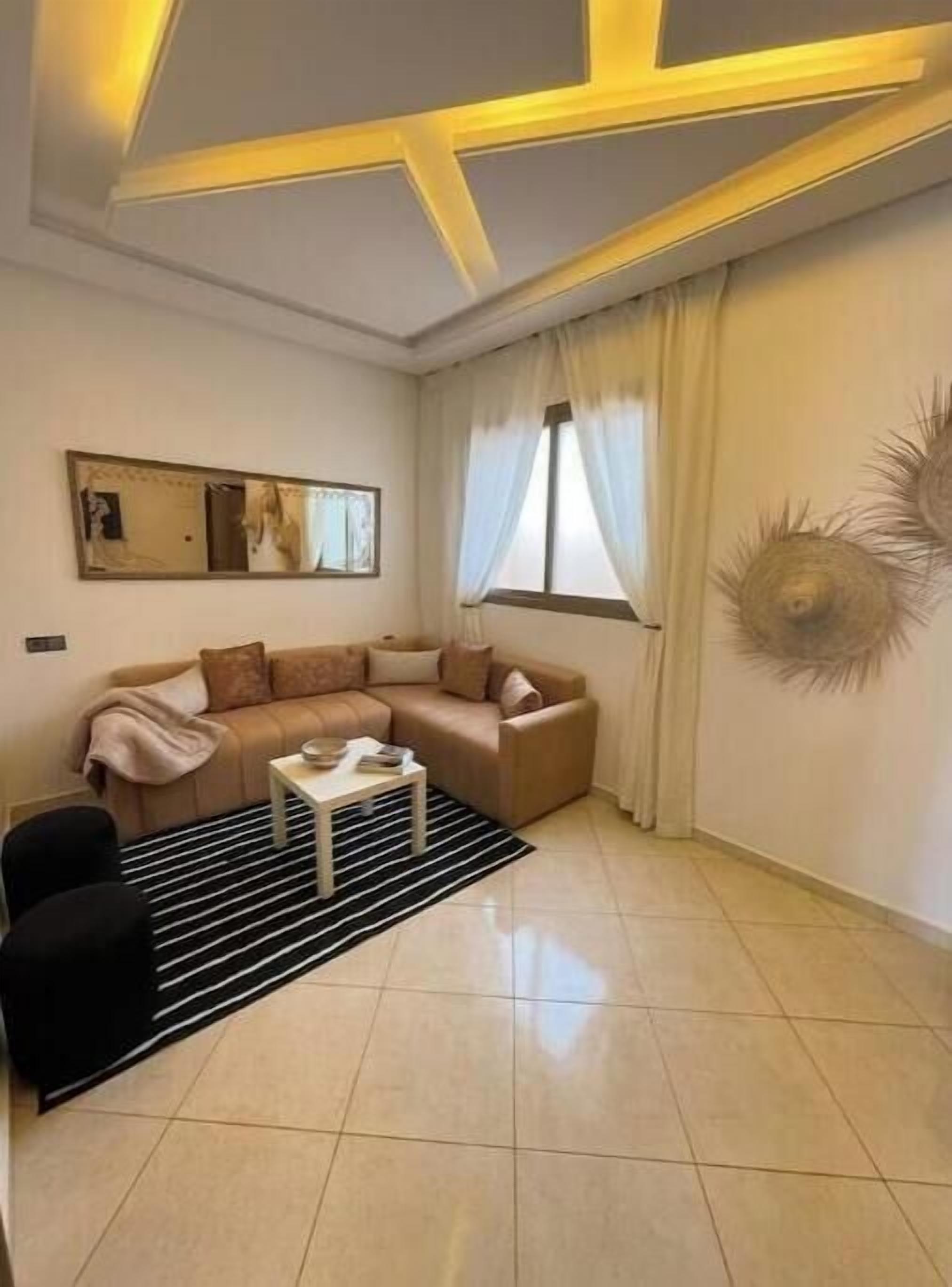 Una sala de estar con un sofá, una mesa de centro, una alfombra y un adorno de pared.