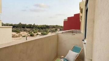 A balcony with a chair, a small table, and a view of the landscape.