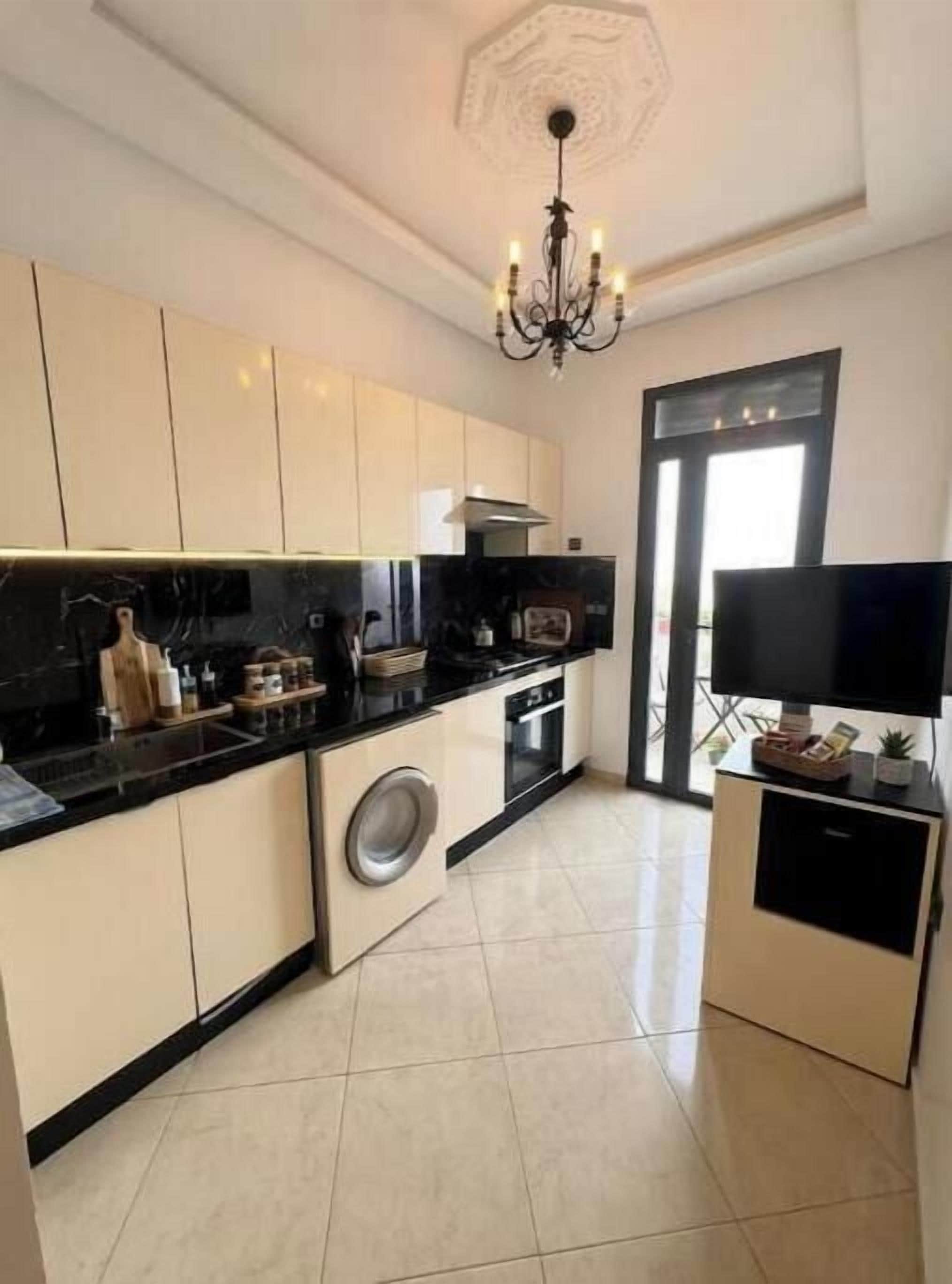 Una cocina moderna con lavadora, televisor de pantalla plana y candelabro.