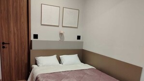 A bedroom with a bed, wooden floor, a door, and two wall-mounted picture frames. - Margot Premier Apartment (Guadalajara)
