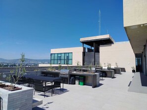 Eine Dachterrasse mit Gartenmöbeln, einem Grill und Blick auf die Skyline der Stadt.