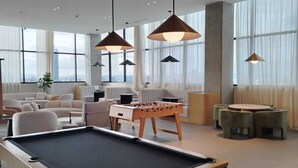 A modern indoor recreational area with a pool table, sofas, and a foosball table. - Margot Premier Apartment (Guadalajara)