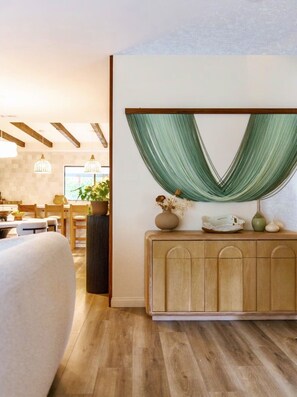 Un interior moderno con un sofá, un mueble de madera y un tejido verde sobre una viga de madera.
