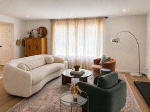 A living room with a sofa, armchair, coffee table, and a lamp. - Stylish Designer Home Near Downtown & Bike Path (Ojai)