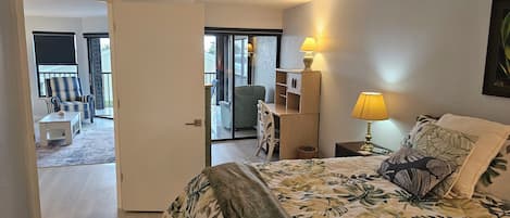 A hotel room with a bed, a nightstand, a lamp, a chair, and a view of the balcony.