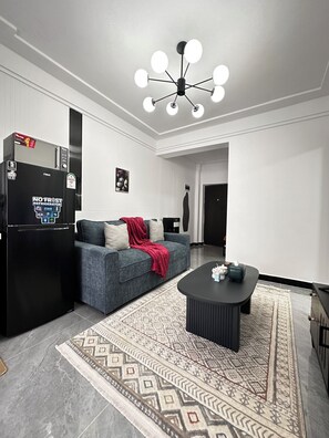 A modern living room with a black refrigerator, a gray sofa with a red throw, a black coffee table, and a patterned rug. - Cozy Modern Mini 2BR, Close to Yaya Centre & Top Cafes.
Gym,kids play pen, (Nairobi)