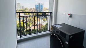 Ein kleiner Balkon mit Blick auf Gebäude und einer Waschmaschine.