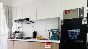 Eine moderne Küche mit weißen Schränken, einem schwarzen Kühlschrank, einer Kaffeemaschine und einem Wasserkocher.