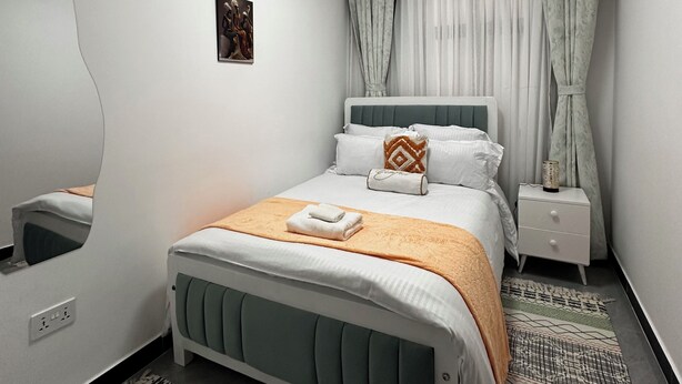 Ein modernes Schlafzimmer mit einem Bett, Nachttischen, einem Spiegel und einer Deckenleuchte.