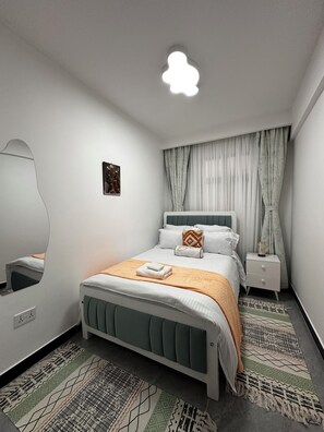 A modern bedroom with a bed, bedside tables, a mirror, and a ceiling light fixture. - Cozy Modern Mini 2BR, Close to Yaya Centre & Top Cafes.
Gym,kids play pen, (Nairobi)