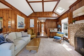 Ein gemütliches Wohnzimmer mit Kamin, Holzwänden, einer Couch und einem Couchtisch.