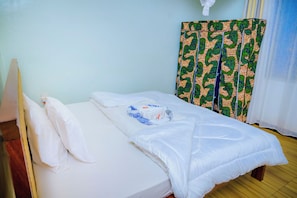 A single bed with white bedding and a blue and white patterned pillow.