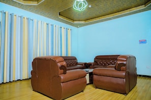 A room with a brown leather sofa set, a wooden floor, and a ceiling with a geometric light fixture. - KEFA TOWN HOTEL (Kigali)