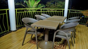 Un área de comedor al aire libre con mobiliario de mimbre y piso de madera.